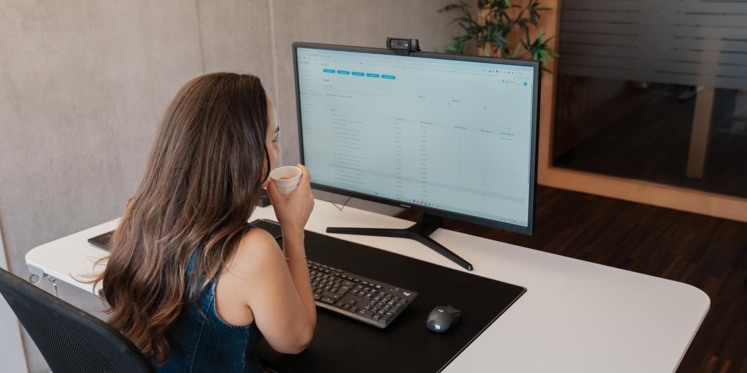 Person von hinten vor einem Computerbildschirm im Loginbereich von publicjobs.ch mit geöffneter E-Rekrutierungs-Software und aktivem Multiposting-Modul zur Veröffentlichung einer Stellenanzeige, helle Benutzeroberfläche mit grauen, blauen und grünen Bedienelementen sowie Büro-Pflanze im Hintergrund.